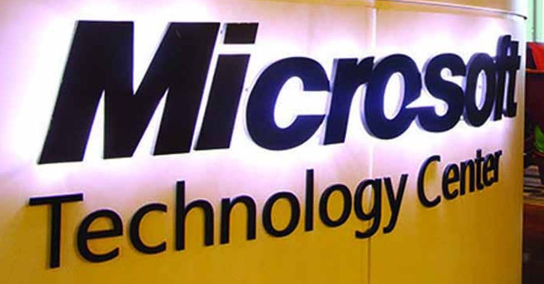 Foto de um balcão amarelo com o logo da Microsoft em preto com iluminação branca e o termo “Technology Center” logo abaixo.