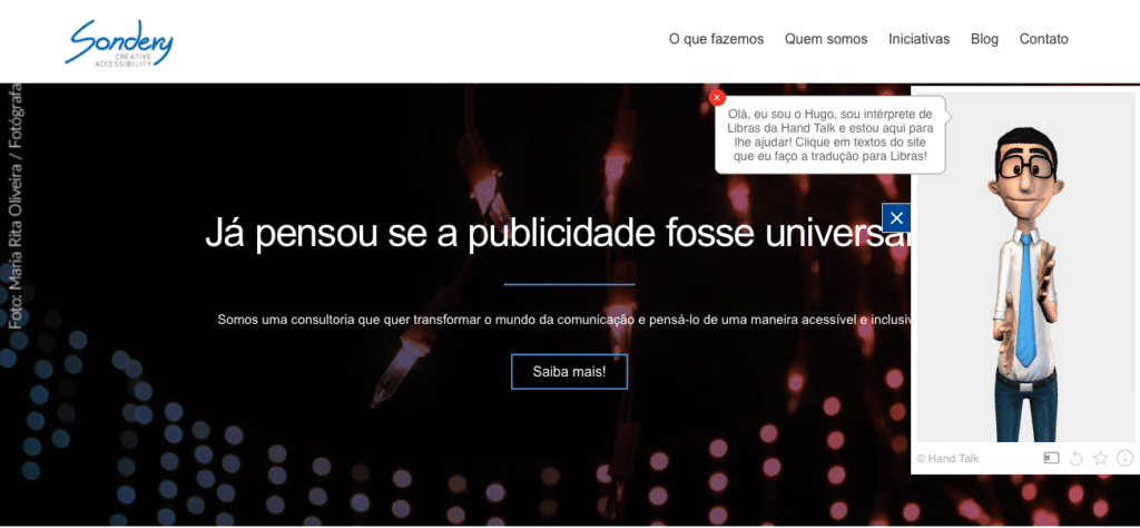 Um print da home page da Sondery com uma janela à direita, onde o Hugo está fazendo o sinal de Libras e um balão diz: Olá, eu sou o Hugo, sou intérprete de Libras da Hand Talk e estou aqui para lhe ajudar! Clique em textos do site que eu faço a tradução para Libras.