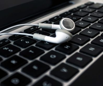 Foto de um fone de ouvido branco sobre um teclado de notebook.