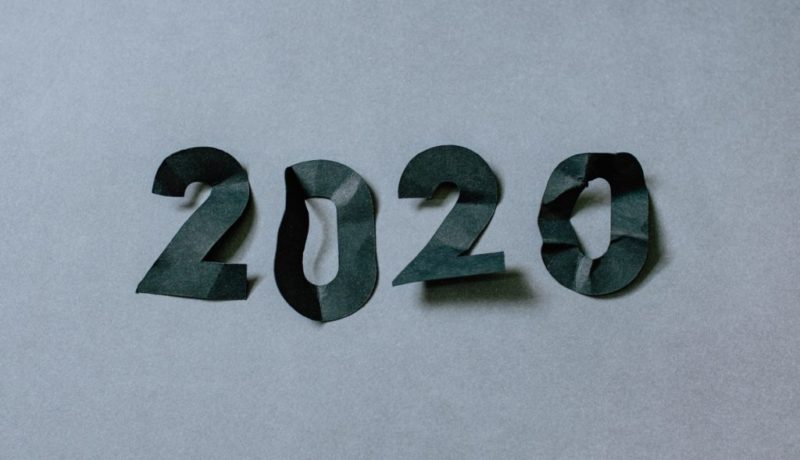 Quatro pedaços de papel preto recortados para formar os números de 2020 sobre um fundo cinza.